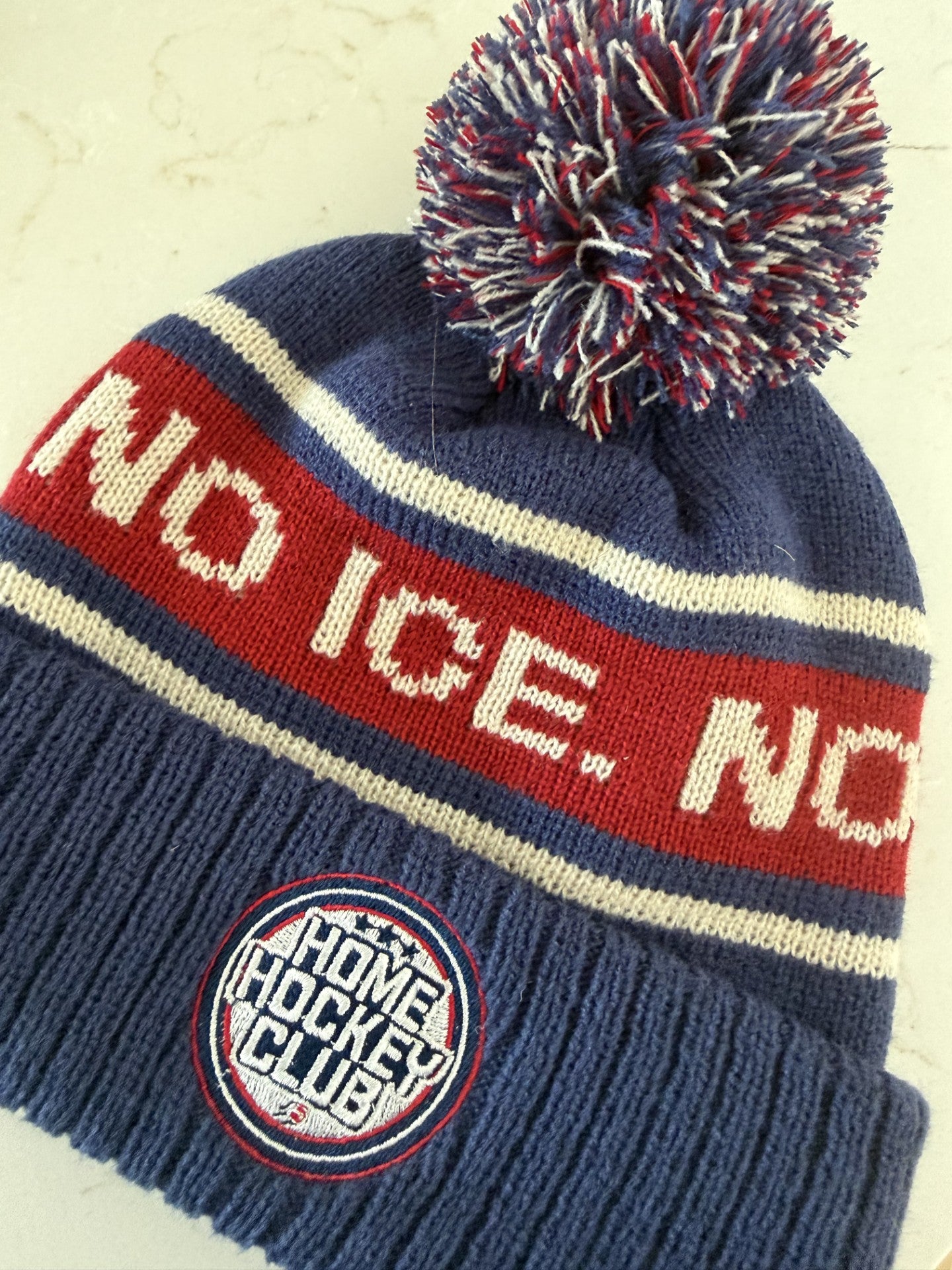 Home Hockey Club navy hockey pom beanie featuring No Ice. No Problem. knit design and embroidered Home Hockey Club patch.